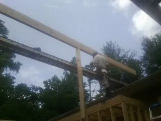 Carpenter setting a ridge beam over a new addition frame — Ice Dam Removal by Roofing Brothers in Labelle
