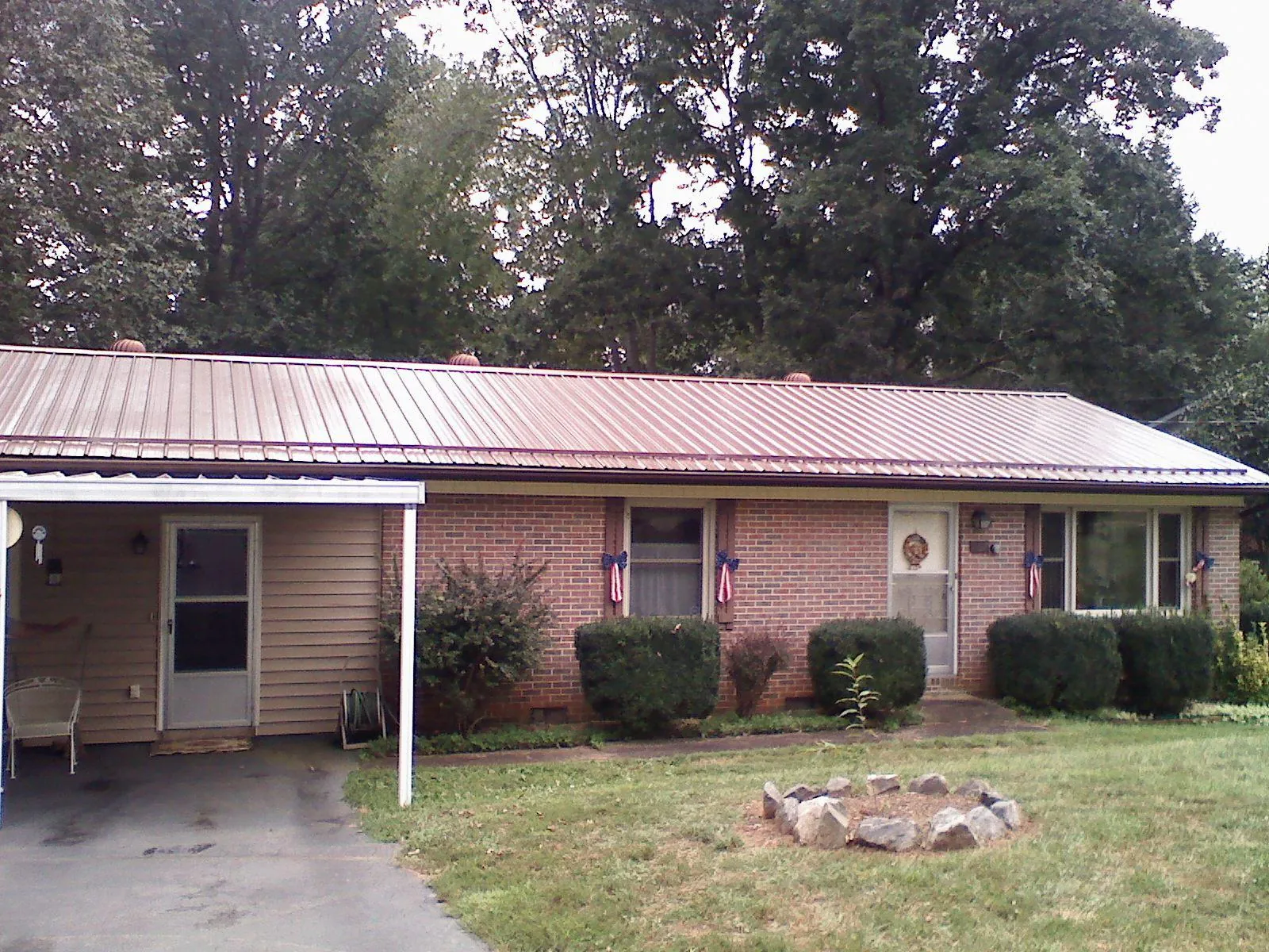 Bronze metal roof and carport on a brick ranch home — Roof Repair work by our crew in Labelle