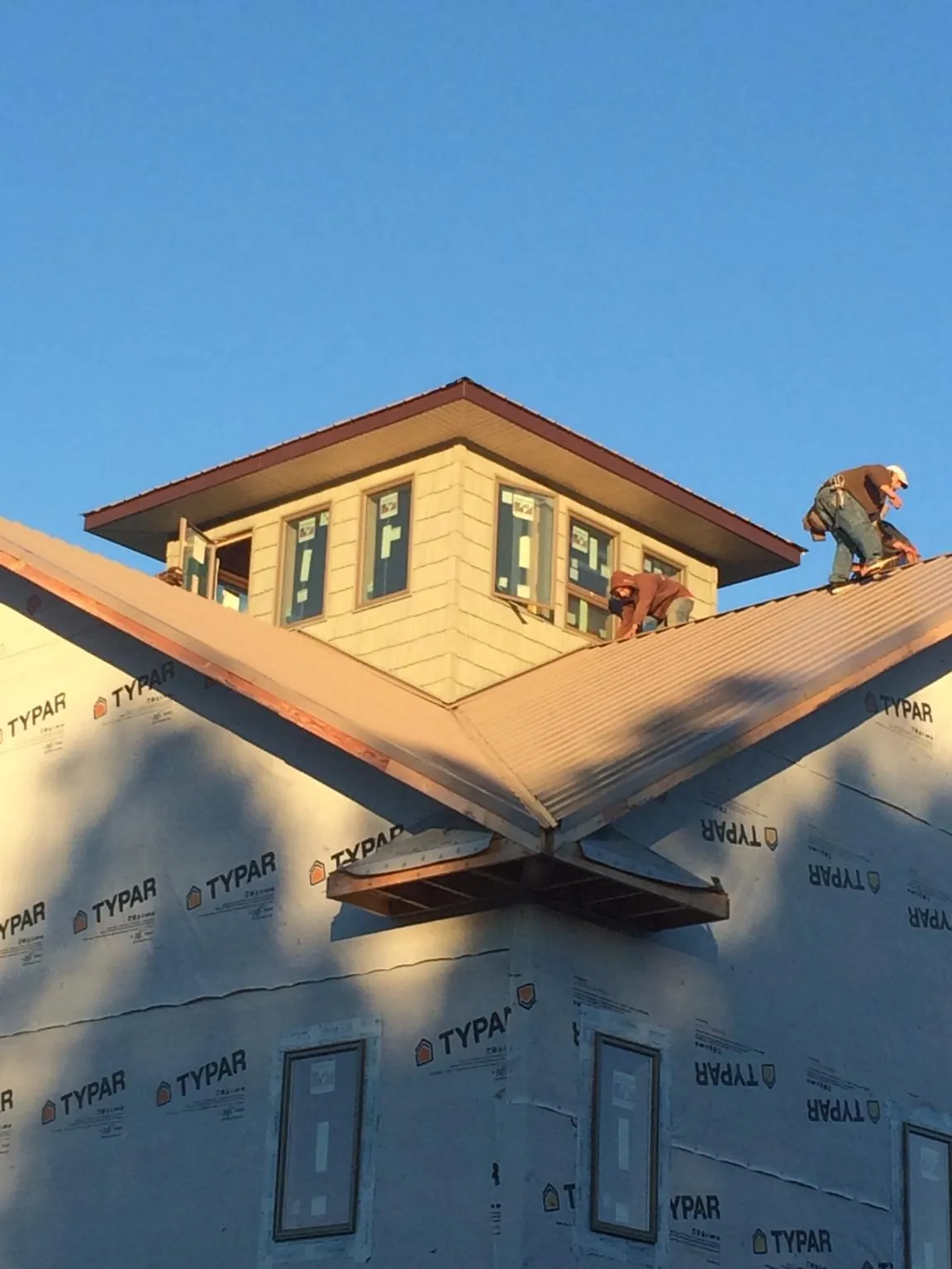 Roofers working around a rooftop cupola on a new metal roof at sunset — Roof Waterproofing in Labelle by Roofing Brothers